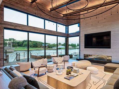 Large living room with sofas, accent chairs, tables, fireplace, TV, and large windows.